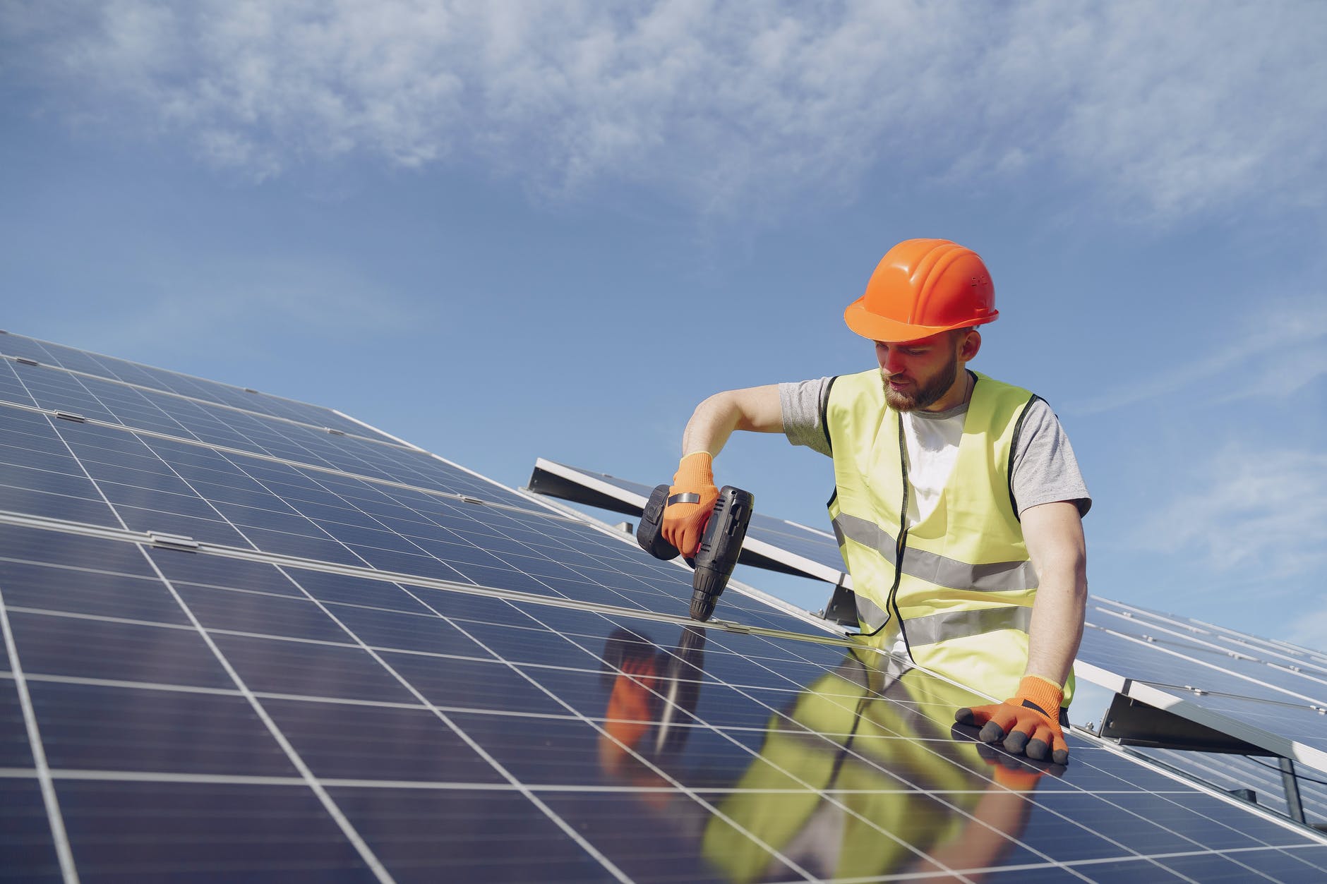 man fixing solar panels with professional drill