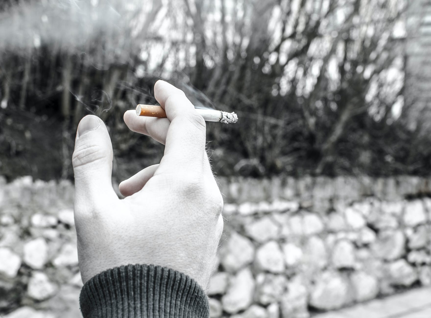 selective color photography of person holding cigarette stick