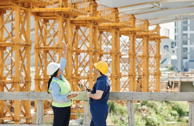 a man and a woman with ppe s talking at a construction site