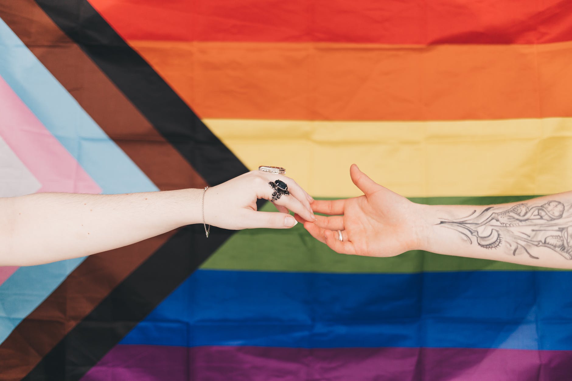 hands joined against progress pride flag