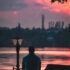 man in a hat sitting at sunset