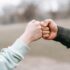 man and happy woman greeting each other with fist bump